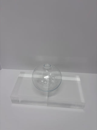 Angled view of vintage clear glass round vase with porthole details on white platform showing sculptural form