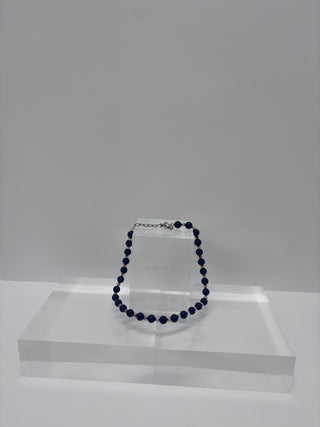 Vintage blue beaded necklace arranged in circular form on white stepped display platform