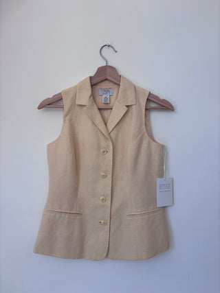 Front view of vintage beige linen vest hanging on wooden hanger against white wall, showing notched lapels, four cream buttons, and patch pockets with original tag attached