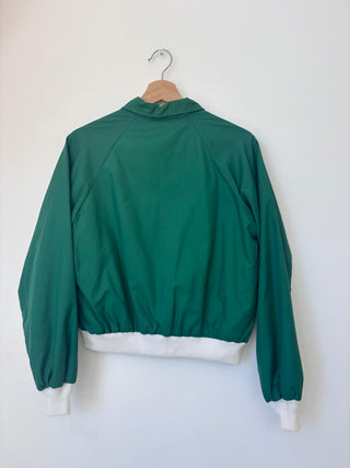Back view of vintage green Masters windbreaker jacket on wooden hanger showing plain back and white ribbed hem and cuffs