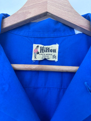 Close-up of Hilton single needle sleeve label tag inside collar of vintage blue work shirt