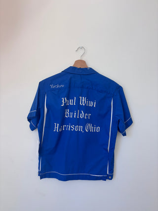 Back view of vintage blue work shirt showing white chain-stitch embroidery reading 'Paul Wiwi Builder Harrison, Ohio' and 'Kocher' on upper back