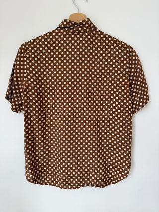 Back view of vintage brown polka dot button-up shirt on hanger showing full pattern and relaxed fit