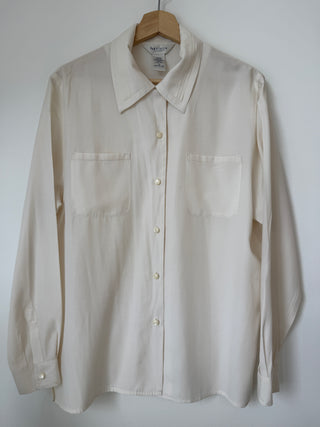 Vintage Van Heusen cream silk blend button-up shirt hanging on wooden hanger against white background, showing front view with pintuck pleating details and chest pockets