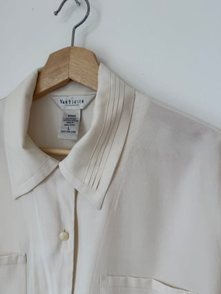 Close-up detail of Van Heusen label and pintuck pleated collar and shoulder, showing cream colored silk blend fabric texture