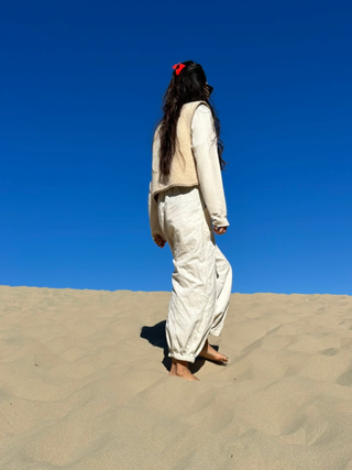 Back view of woman standing on sand with blue sky wearing hair pulled back with red claw clip