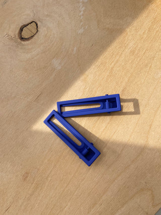 Nat + Noor Cobalt Blue Alligator Hair Clips on wooden surface