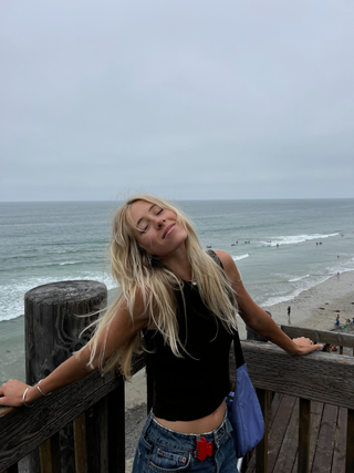 Woman standing in front of ocean with hair claw clipped onto belt loop of jeans