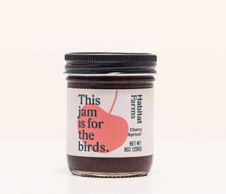 Habitat Farms Cherry Apricot jam jar with pink label reading 'This jam is for the birds' against cream background