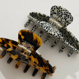Close-up of metal spring clasp mechanism on leopard print and tortoiseshell claw clips showing hardware detail