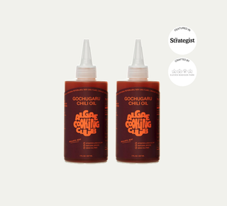 Two bottles of Gochugaru Chili Oil side by side with white caps, featured in The Strategist and crafted by Eleven Madison Park