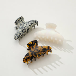 Three classic curved claw clips in leopard print, tortoiseshell, and white displayed on white surface with shadows
