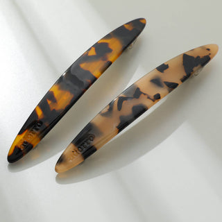 Close-up of two tortoiseshell French barrettes showing dark amber and lighter brown marbled patterns