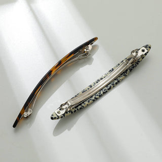 Underside view of tortoiseshell and leopard print barrettes showing automatic metal clasp mechanism