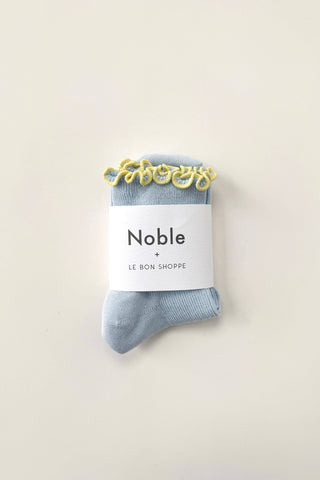 Light blue petite ruffled modal socks wrapped with Noble and Le Bon Shoppe branded paper band