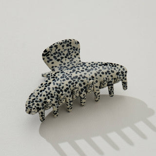 Leopard print curved claw clip with small black spots on cream background, side angle view on white surface